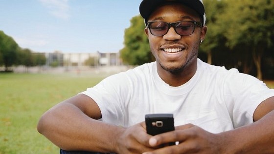 African American man in park using cell phone