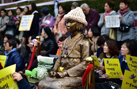Protestors in Seoul sit next to a statue of a South Korean teenage girl in traditional costume called the "peace monument" for women used as sex slaves by Japanese soldiers during World War II (AFP Photo/Jung Yeon-Je)