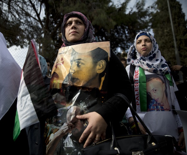 Family members of Mohammed Abu Khdeir, hold posters with his portrait after the reading of the verdict in his killing, at the Jerusalem District Court, Monday, Nov. 30, 2015. The court on Monday convicted two Israeli youths in the grisly killing of Abu Khdeir, while delaying a verdict for 31-year-old Yosef Haim Ben David in the case due to a last-minute insanity plea. The judge determined that Ben David, and two Israeli minors had snatched Abu Khdeir from an east Jerusalem sidewalk in July 2014 and burned him alive in a forest outside the city. (AP Photo/Oded Balilty)