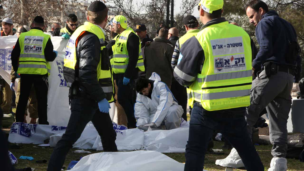 Israeli police forensic experts examine a body of one of the four Israeli soldiers killed when a Palestinian truck driver ran over a group of soldiers at the Jerusalem promenade on January 8, 2017. A Palestinian rammed a truck into a group of Israeli soldiers visiting a popular tourist spot in Jerusalem, killing four and wounding at least 15 people, authorities said. Gali TIBBON / AFP