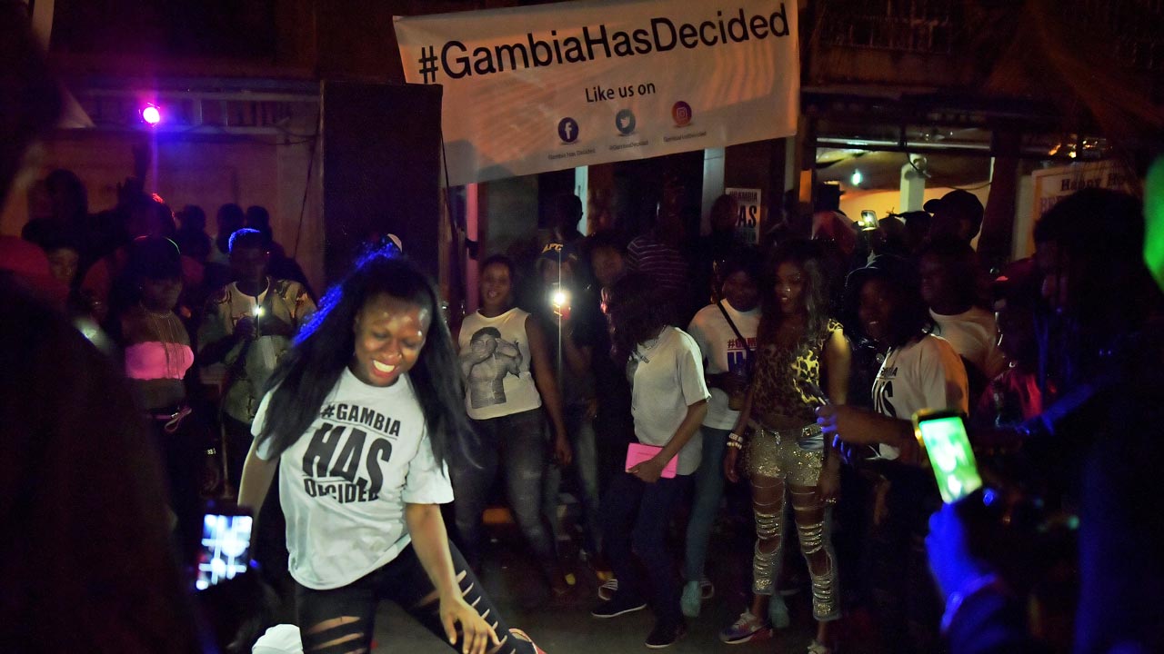 People dance in the streets after hearing of the confirmed departure of former Gambian leader Yahya Jammeh in Banjul on January 21, 2017. Yahya Jammeh, The Gambia's leader for 22 years, flew out of the country on January 21, 2017 after declaring he would step down and hand power to President Adama Barrow, ending a political crisis. An AFP journalist at the airport saw Jammeh board an unmarked plane heading for an unspecified destination, seen off by a delegation of dignitaries and soldiers. CARL DE SOUZA / AFP
