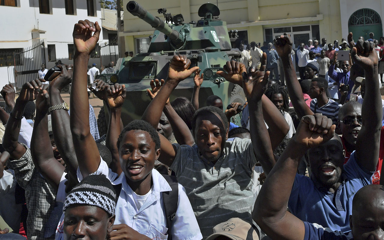 Gambians celebrate outside of the Statehouse in Banjul on January 23, 2017. The Gambia on January 23 awaited the arrival of President Adama Barrow as his team said former strongman Yahya Jammeh plundered the nation's coffers before going into exile. Barrow, who was sworn in as the new head of state on January 19 at his country's embassy in neighbouring Senegal, has put off his return over fears for his safety. / AFP PHOTO / CARL DE SOUZA