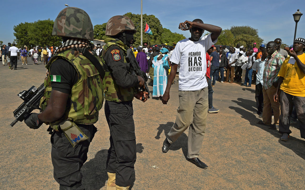 Soldiers of the Nigerian Special Boat Service (SBS) stand guard as people wait for the arrival of President Adama Barrow (not pictured) at the airport in Banjul on January 26, 2017. Jubilant Gambians on Janauary 26 welcomed home their new President Adama Barrow, who was elected almost two months ago but forced to flee to Senegal when his predecessor refused to step aside. Dressed in flowing white robes and cap, Barrow stepped off the plane, with heavily-armed troops from Senegal and Nigeria standing by as he flew in from Dakar where he had taken shelter on January 15./ AFP PHOTO / CARL DE SOUZA