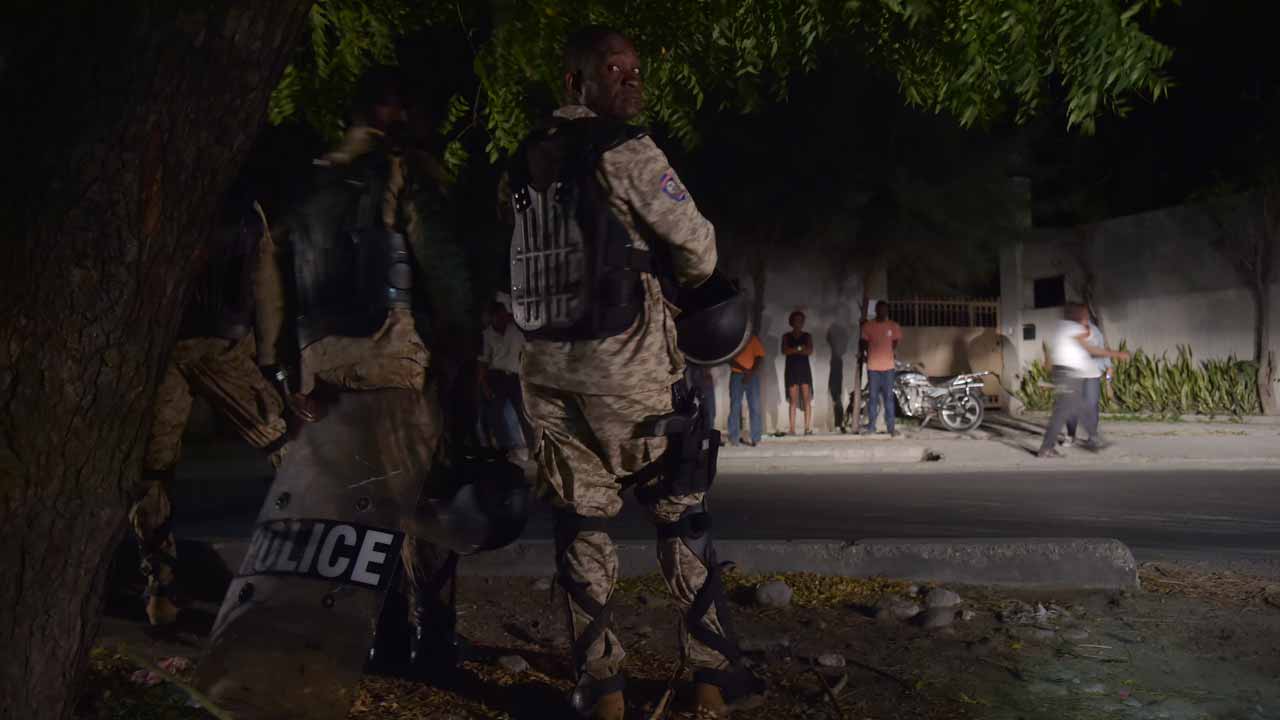 Members of the Haitian Police stand guard in front of the Centrale de la Police Judiciaire (DCPJ), in Port-au-Prince, on January 5, 2017, while some of supporters of Guy Philippe protest against his arrest. Onetime Haiti coup leader Guy Philippe, who has long been wanted by US authorities on drug trafficking charges but was recently elected to the country's senate, was arrested, police said. HECTOR RETAMAL / AFP