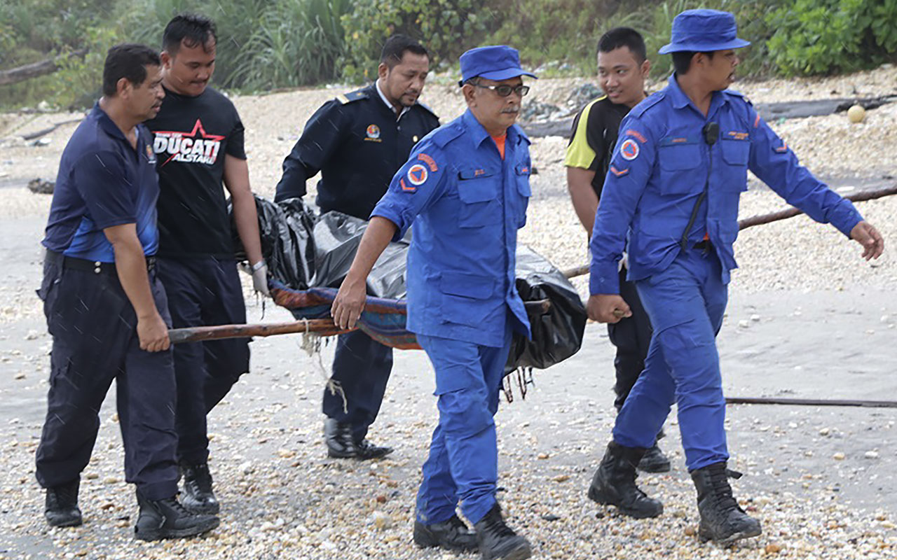 This handout from the Malaysian Maritime Enforcement Agency taken on January 23, 2017 shows rescuers carrying a body retrieved from a search operation near the area where a boat carrying Indonesian immigrants capsized in Mersing, in Malaysia's southern Johor state. Ten people are confirmed dead and about 30 missing after a boat believed to be carrying Indonesian illegal immigrants capsized in rough seas off Malaysia, officials said on January 23. / AFP PHOTO / MALAYSIAN MARITIME ENFORCEMENT AGENCY / Handout / 