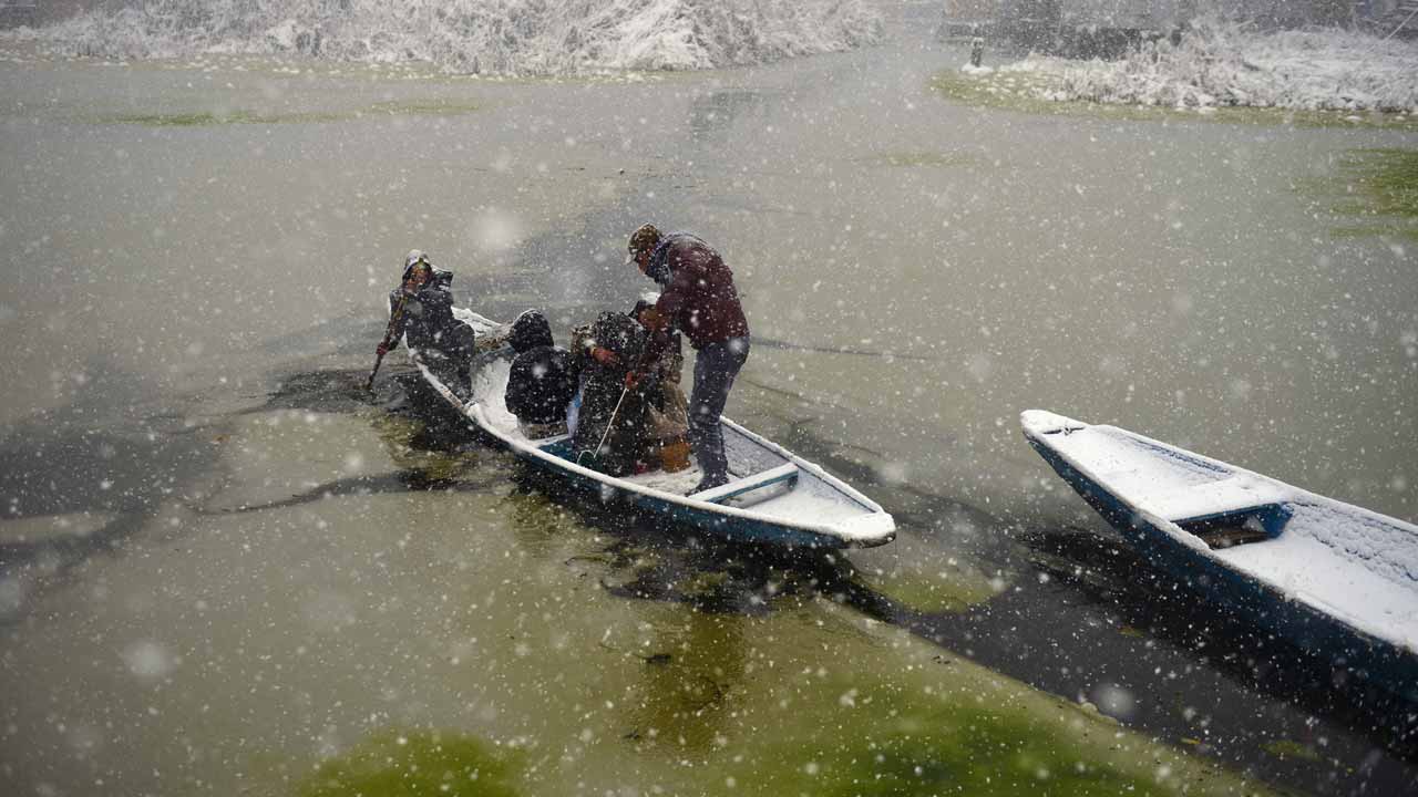 An Indian Kashmiri boatman transports passengers during heavy snowfall on Dal Lake in Srinagar on January 6, 2017. Indian-administered Kashmir has been cut off from the rest of the country after heavy snowfall closing the 294km Jammu-Srinagar national highway, the only road link between Kashmir and rest of the country. TAUSEEF MUSTAFA / AFP