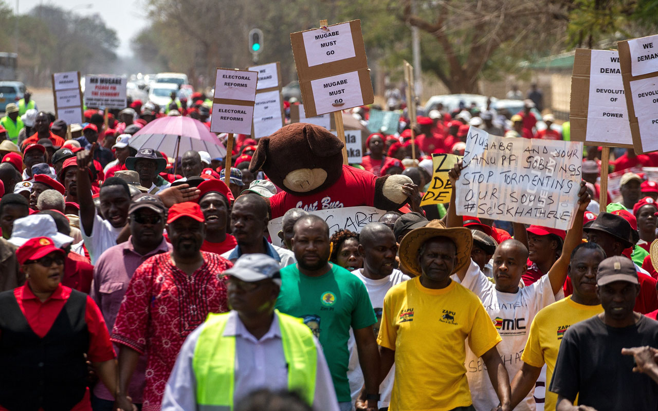  protesters holding placards as Zimbabwe opposition supporters under the National Electoral Reform (NERA) coalition march through the streets of Zimbabwe's second largest city Bulawayo to demand electoral reforms. For opponents of Zimbabwe's veteran President Robert Mugabe, internet data charges have become a key battlefront in their campaign against a regime that often cracks down violently on dissent. Last week, the state's telecommunications authority approved a sharp increase in mobile data prices -- triggering a furious public response that forced a surprise U-turn. Facebook, Twitter and WhatsApp activity was a driving force behind a new protest movement last year that led to work boycotts and street demonstrations that shook the regime of 92-year-old Mugabe. / AFP PHOTO / ZINYANGE AUNTONY