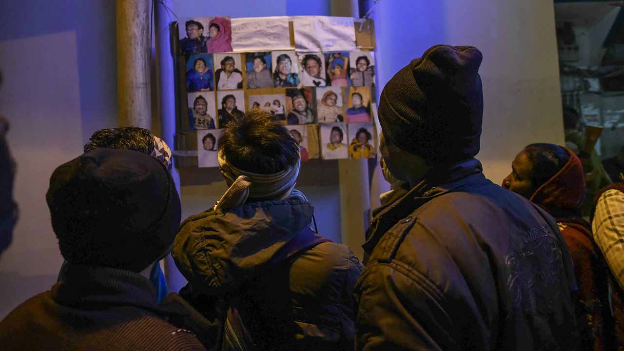 Relatives look at the images of people who drowned in a boat accident on the river Ganges near Patna in eastern India, on January 15, 2017. At least 19 people died January 14 after a boat carrying some 40 revellers returning from a kite festival capsized in the Ganges river in eastern India, police said. AFP