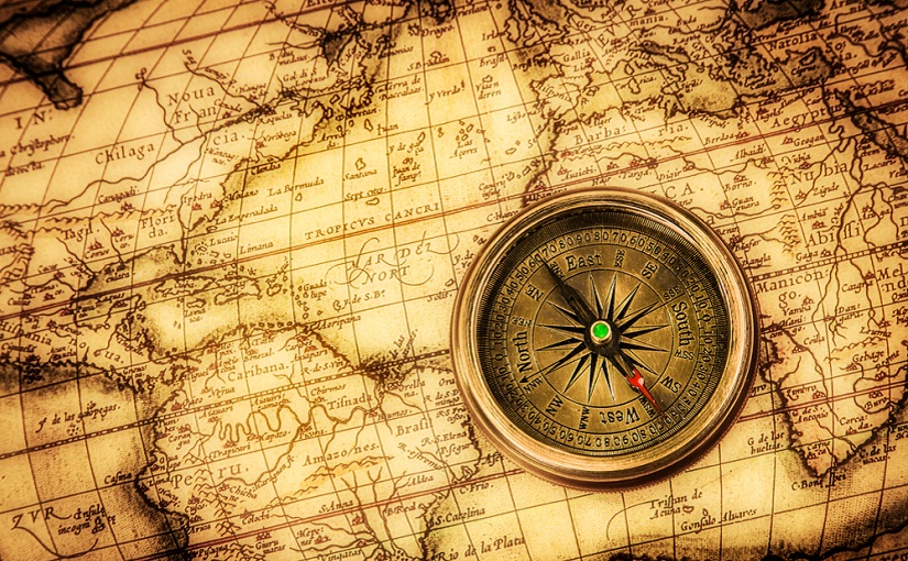 Vintage compass lies on an ancient world map.