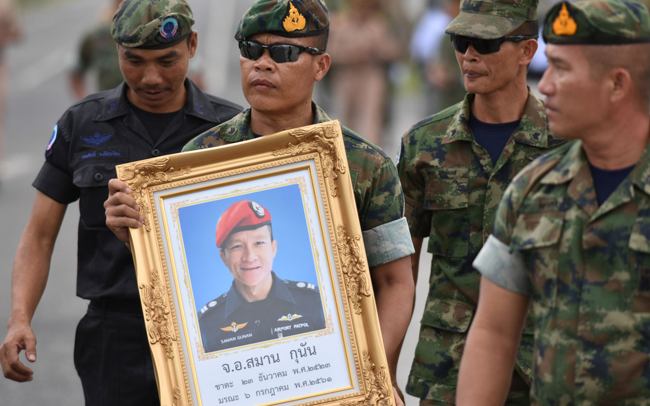 An honour guard hold up a picture of Samarn Poonan, 38, a former member of Thailand’s elite navy SEAL unit who died working to save 12 boys and their soccer coach trapped inside a flooded cave as family members weep at a airport, in Rayong province