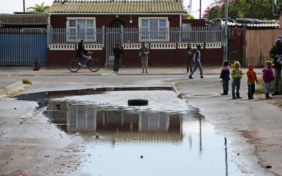 Children are seen near a puddle of water after heavy rains in drought-hit Cape Town