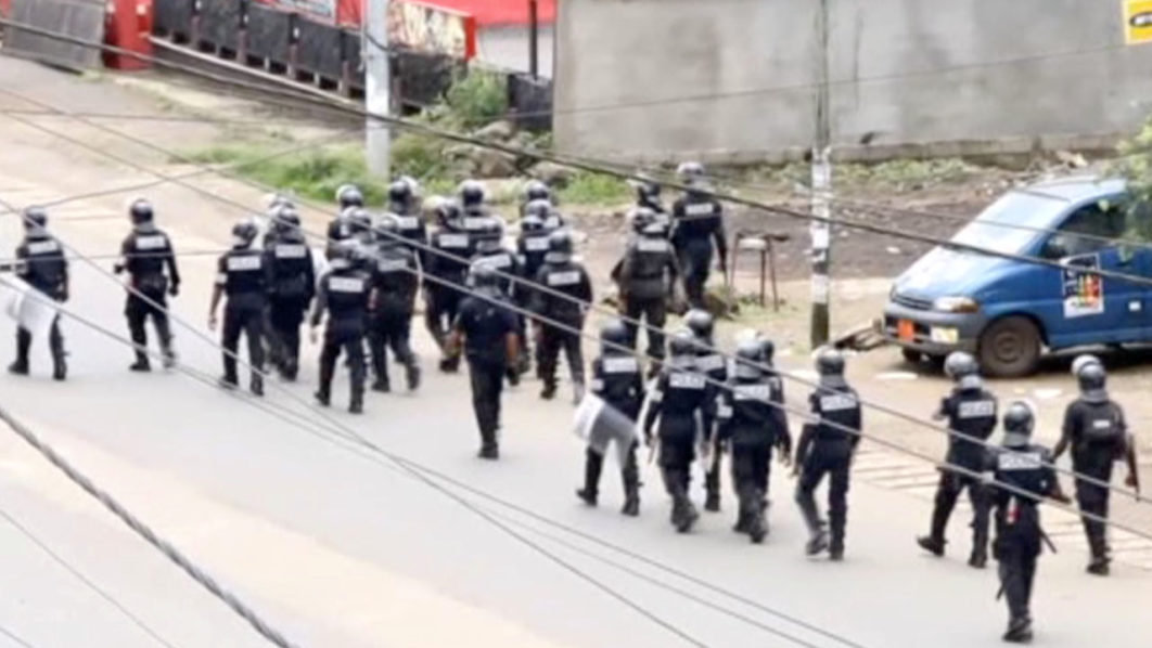A still image taken from a video shows riot police walk along a street in the English-speaking city of Buea