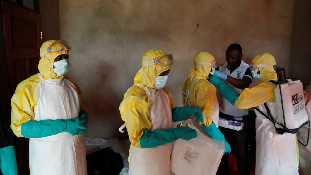 Healthcare workers adjust gear during a funeral of Kavugho Cindi Dorcas who is suspected of dying of Ebola in Beni