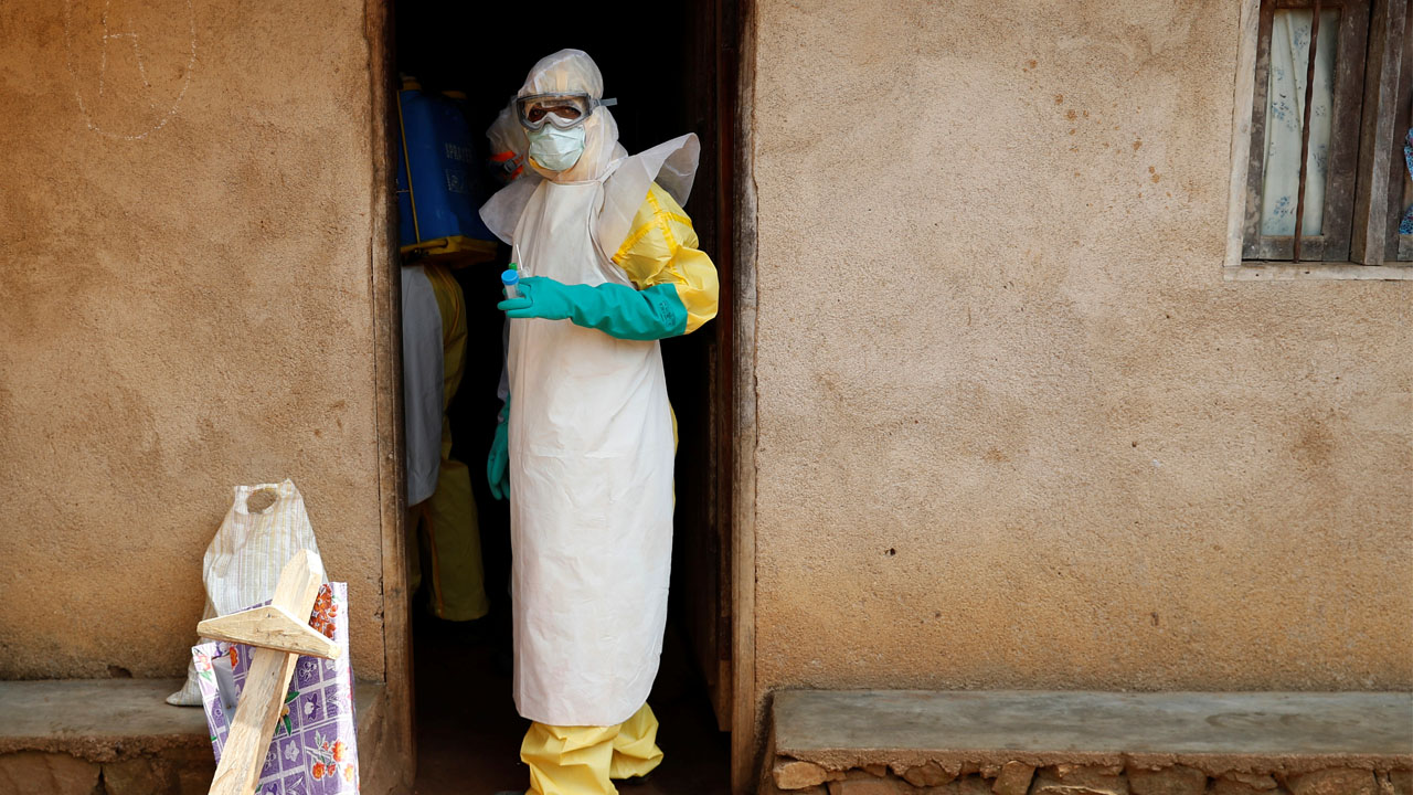 Healthcare workers enter a house where a baby suspected of dying of Ebola is, during the funeral in Beni