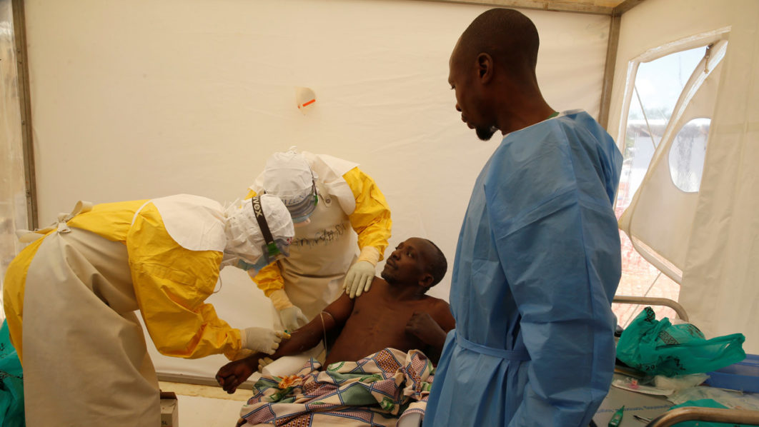 Medical stuff and an Ebola survivor treat Ebola patient Ibrahim Mupalalo inside the Biosecure Emergency Care Unit  at the ALIMA  Ebola treatment centre in Beni