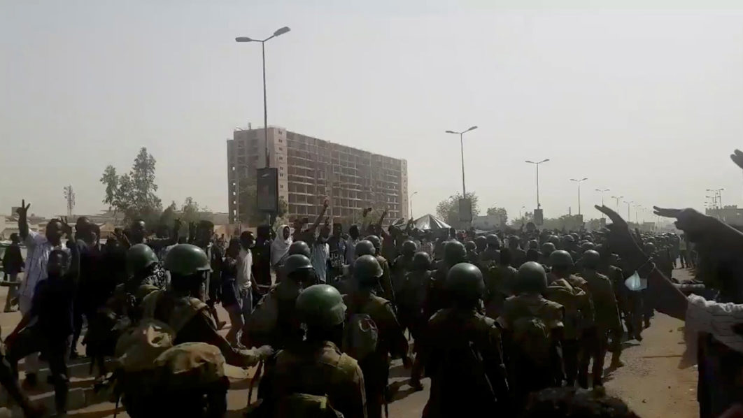 Demonstrators salute soldiers during a protest in Khartoum