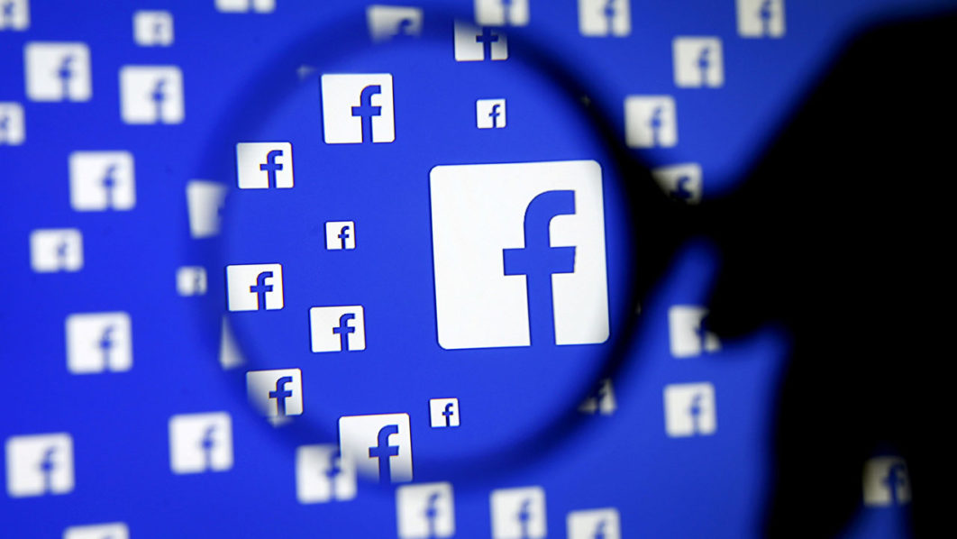 FILE PHOTO: A man poses with a magnifier in front of a Facebook logo on display in this illustration taken in Sarajevo