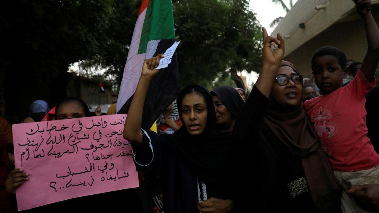 Sudanese people hold banners and march during a demonstration in Khartoum