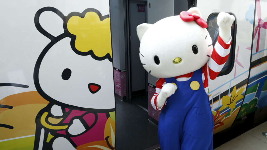 A performer dressed as a Hello Kitty poses next to Hello Kitty-themed Taroko Express train in Taipei, Taiwan