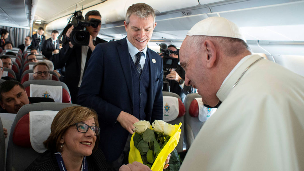 Pope Francis accompanied by a member of the Holy See Press Office Matteo Bruni talks with people on board of a plane to Panama City