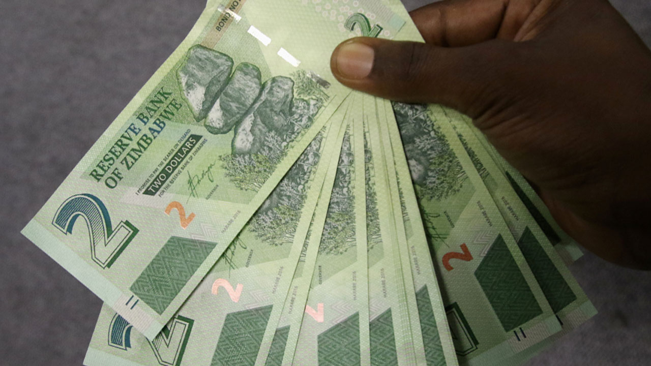 A Zimbabwean man poses with new bond notes outside a bank in the capital Harare