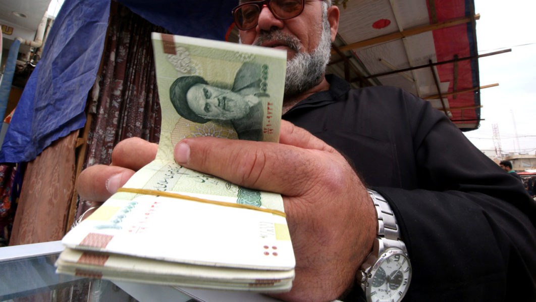 A man buys Iranian rials from a seller of Iranian currency, before the start of the U.S. sanctions on Tehran, in Basra