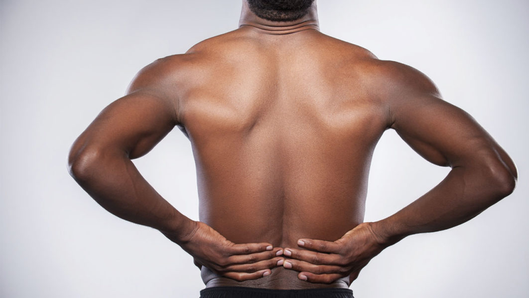 Backache. Rear view of young muscular African man touching his h