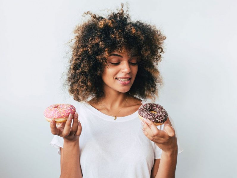 A woman holding sugary doughnuts
