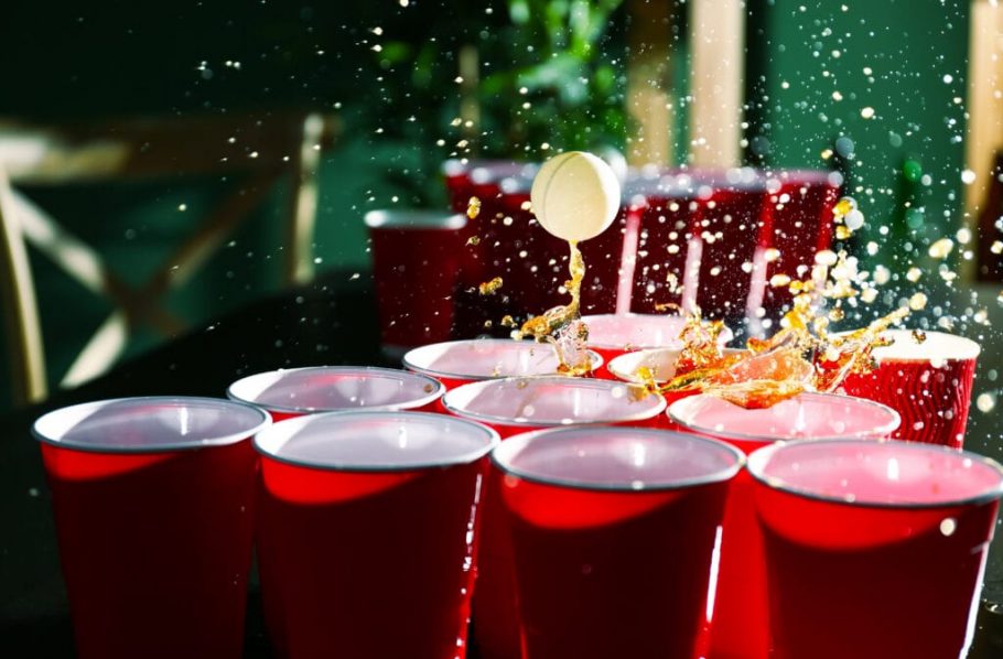 Cups and plastic ball for beer pong game on table