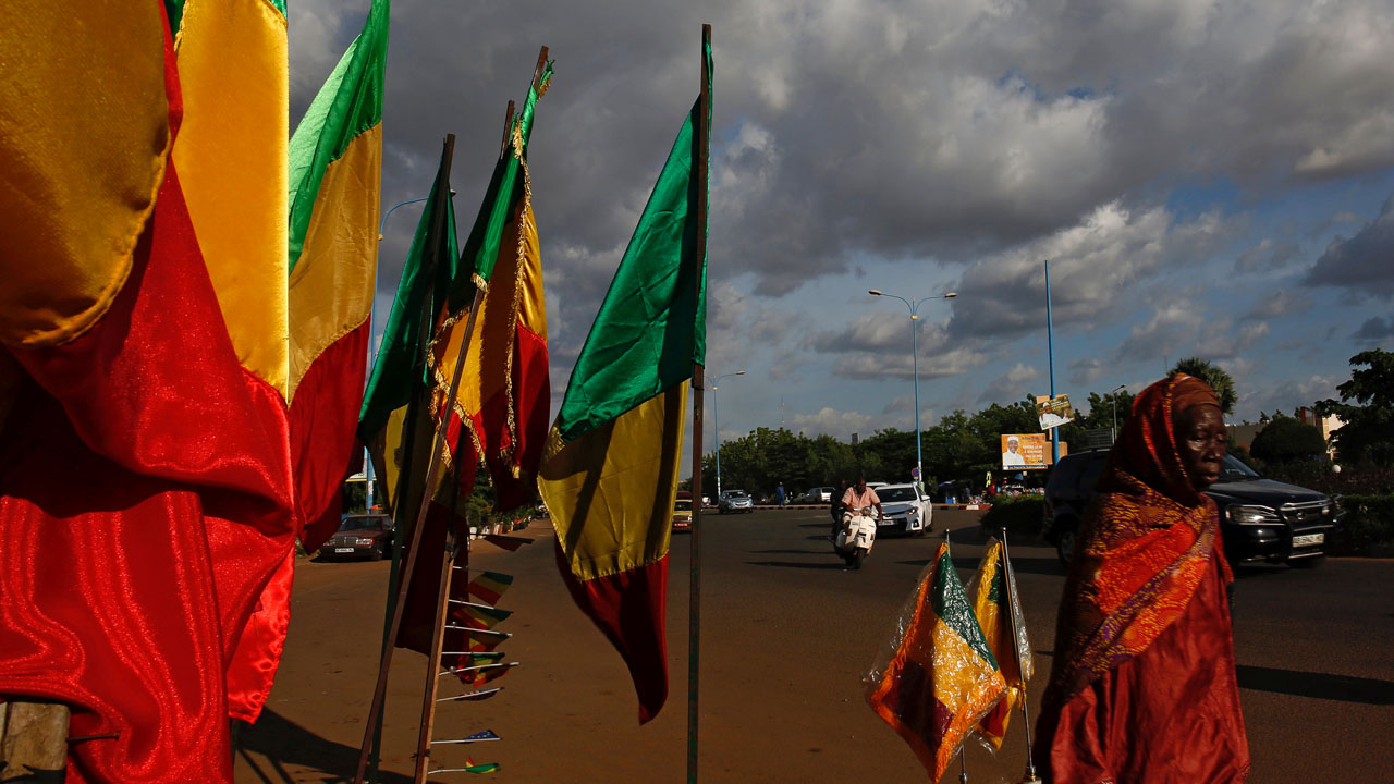 A woman walks past Malian flags in Bamako