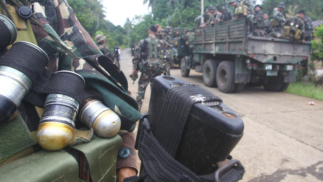 Soldiers stand guard on a road as they are deployed to remote villages in Jolo