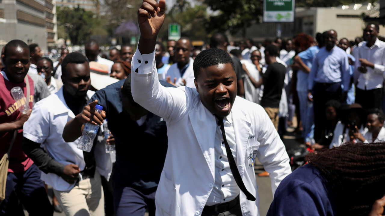 Doctors sing and hold placards during a protest over the disappearance of the leader of their union in Harare