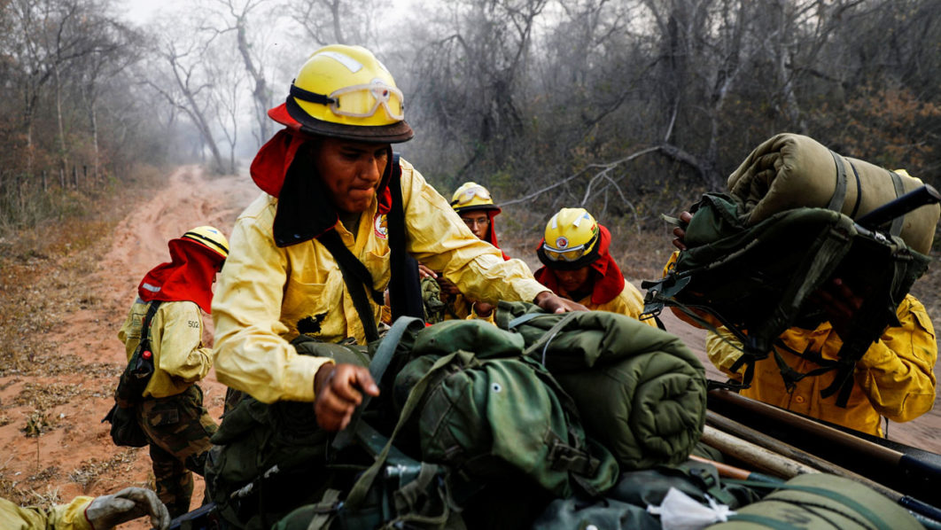 A firefighter from Bolivia’s army places backpacks on a pickup truck before patrolling an area where wildfires have destroyed hectares of forest at Rancho Grande village in Robore