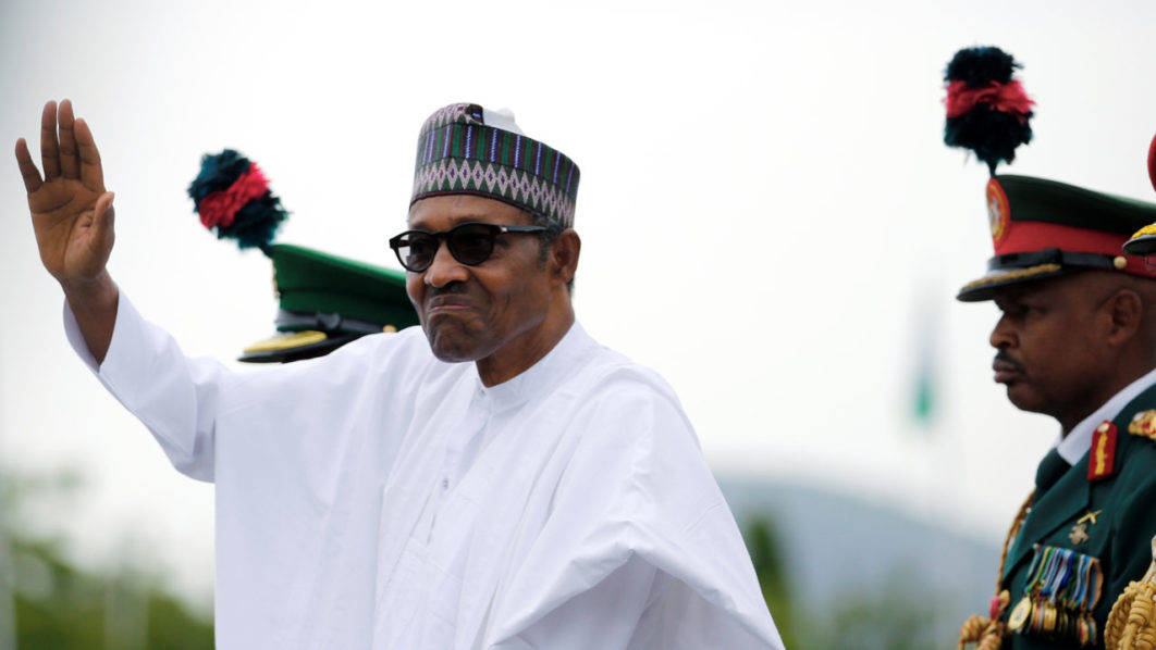 Nigerian President Muhammadu Buhari waves at the crowd while he drives around the venue during his inauguration for a second term in Abuja