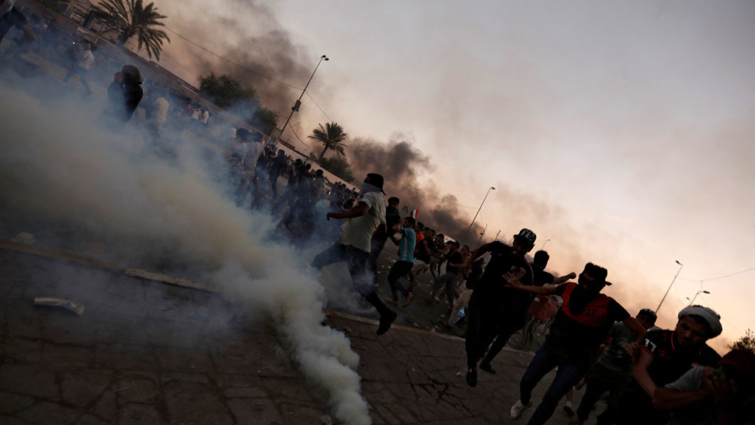 FILE PHOTO: Demonstrators disperse as Iraqi security forces use tear gas during a protest after the lifting of the curfew, following four days of nationwide anti-government protests that turned violent, in Baghdad