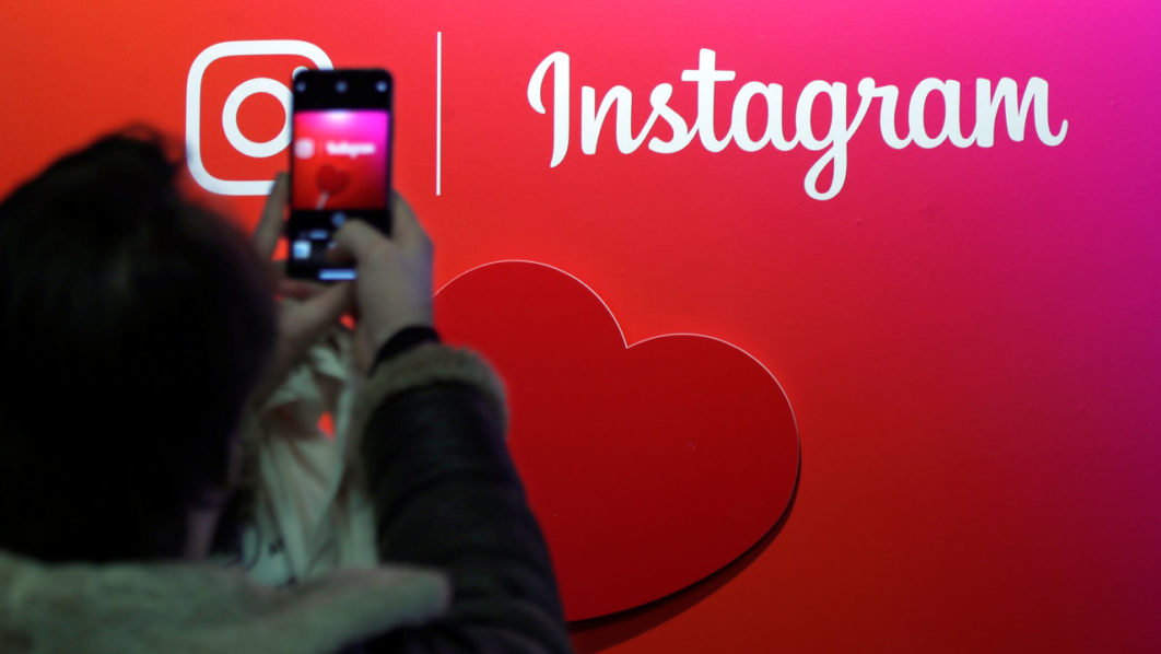 A visitor takes a picture of the Instagram application logo at the Young Entrepreneurs fair in Paris