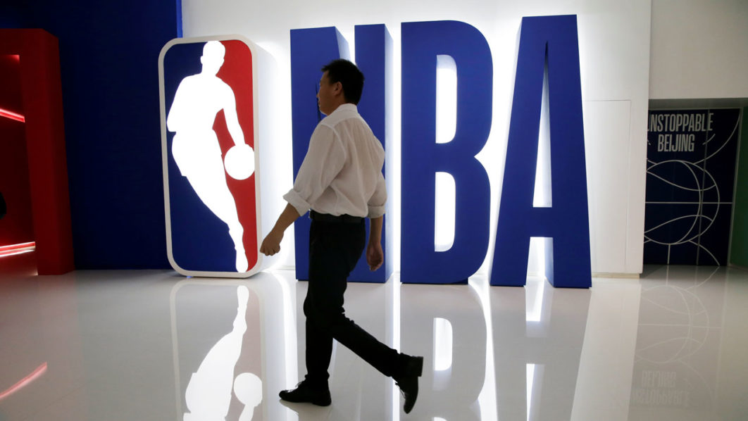 A man walks past an NBA logo at an NBA exhibition in Beijing