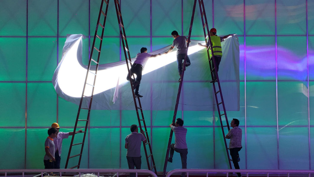 Workers install a Nike logo lamp outside the Wukesong Arena in Beijing