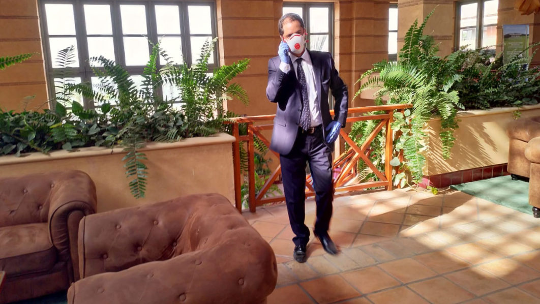 An employee wears a protective mask as he talks on the phone inside a hotel under lockdown after a coronavirus case was identified in Adeje