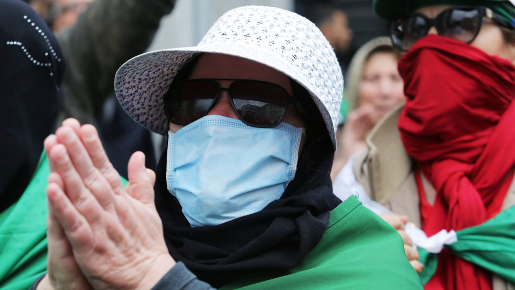 A demonstrator wearing a face mask gestures during an anti-government protest in Algiers