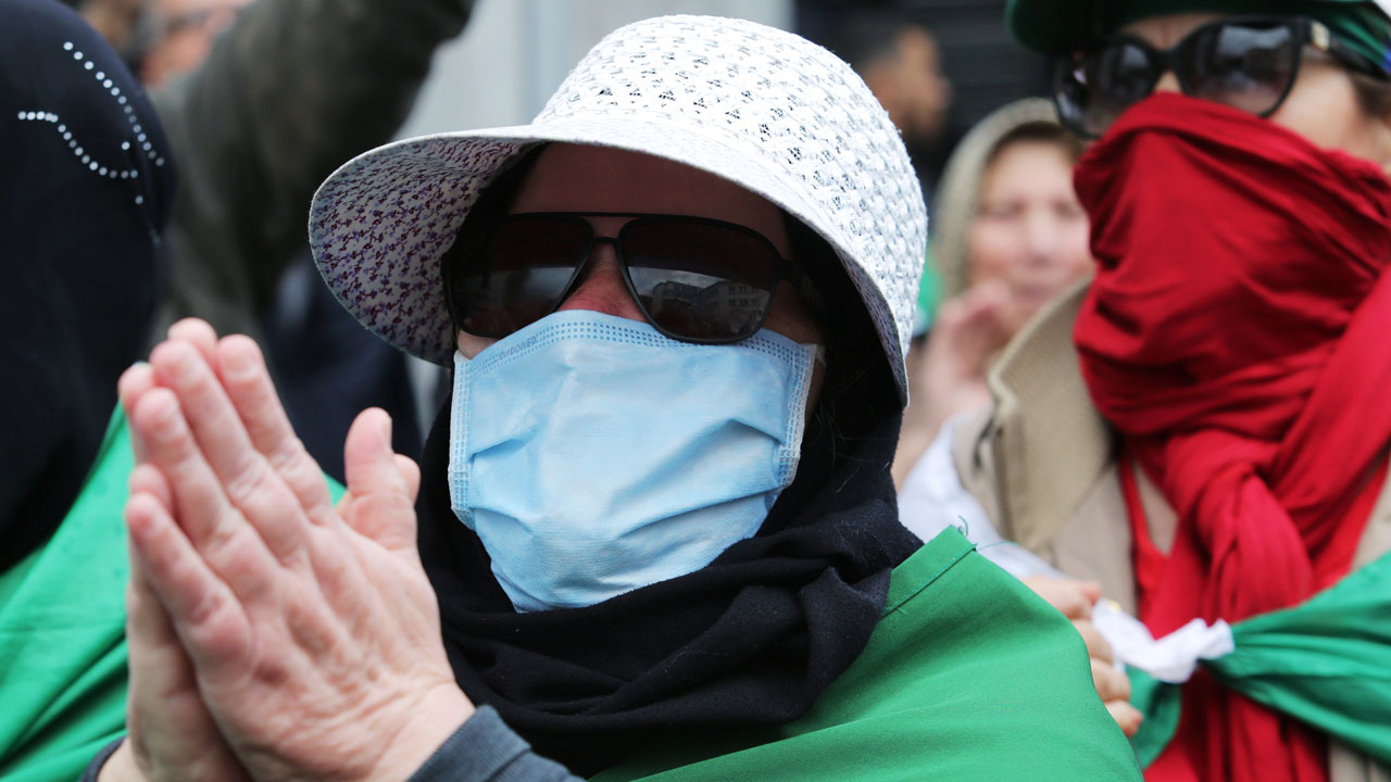 A demonstrator wearing a face mask gestures during an anti-government protest in Algiers