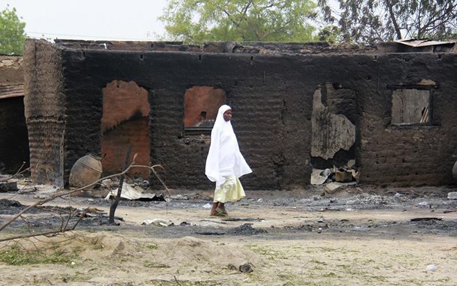 A woman walks past burnt houses in the aftermath of what Nigerian authorities said was heavy fighting between security forces and Islamist militants in Baga