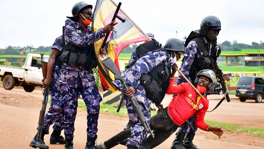 Ugandan riot policemen detain a supporter of presidential candidate Robert Kyagulanyi, in Luuka district