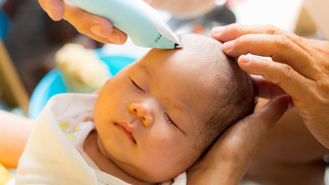 A baby’s hair goes under the clipper. Photo FirstCry Parenting