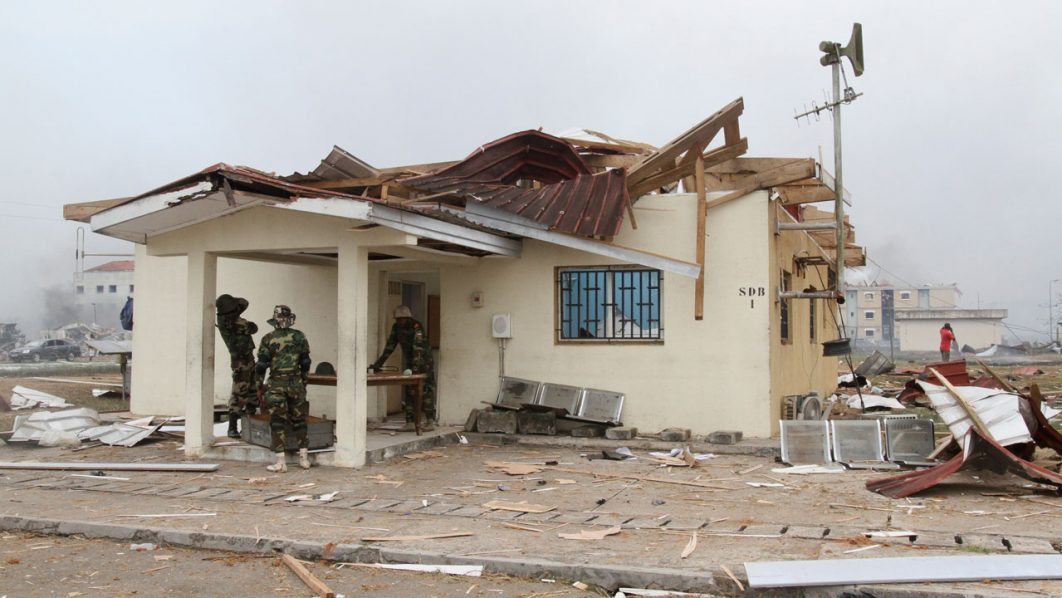 Members of the Army check a damaged house following explosions at a military base