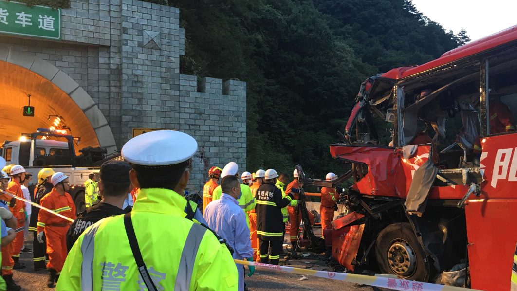 Police and firefighters work near the wreckage of a coach after it crashed into the wall of a tunnel along the Xi’an-Hanzhong expressway in Ankang