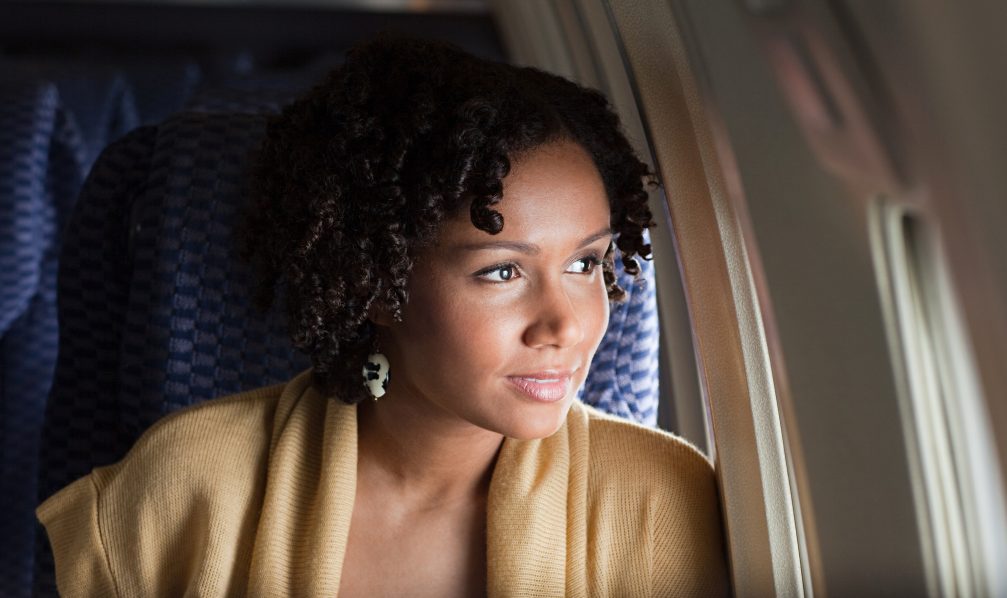 Woman looking out the window on airplane – Image – Getty Images