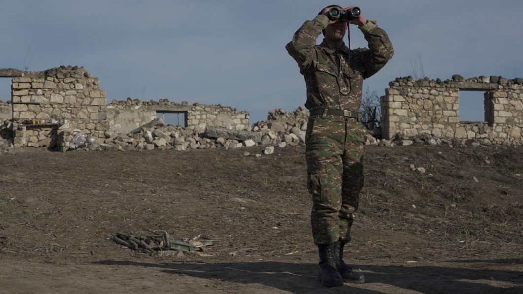 FILE PHOTO: An ethnic Armenian soldier looks through binoculars as he stands at fighting positions near divided Taghavard village in Nagorno-Karabakh region