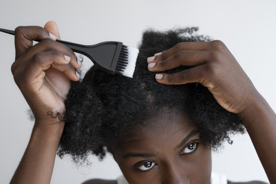 Photo of woman putting relaxer in her hair from Freepik