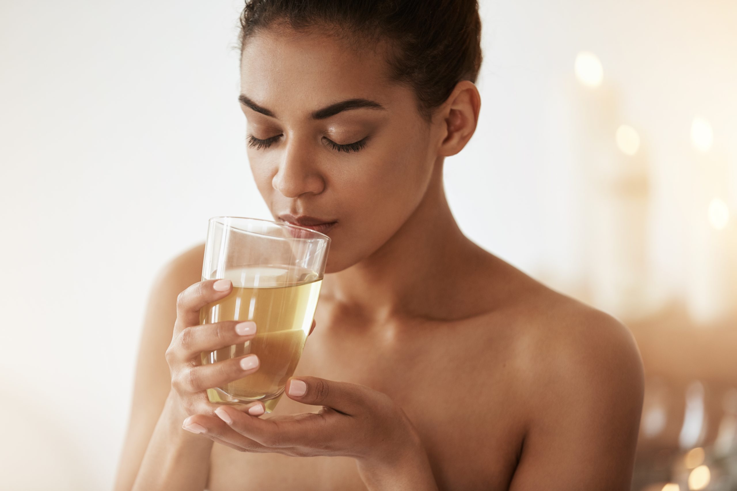 Beautiful african girl drinking tea smiling relaxing in spa salon. Closed eyes.